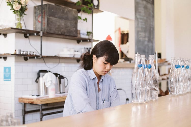 A server refills water bottles behind the bar.