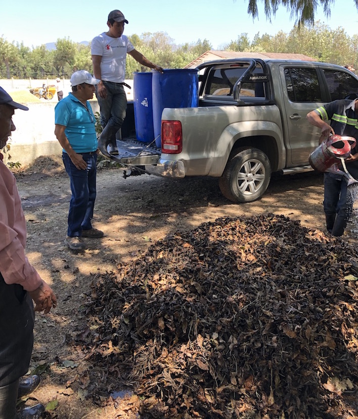 Farmer compost training with Los Volcanes. Coffee farmers look at their composting pile while standing next to a truck.