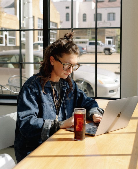 Nora 2 Nora Brady works on a computer at Blueprint Coffee's High Low location while drinking an iced coffee