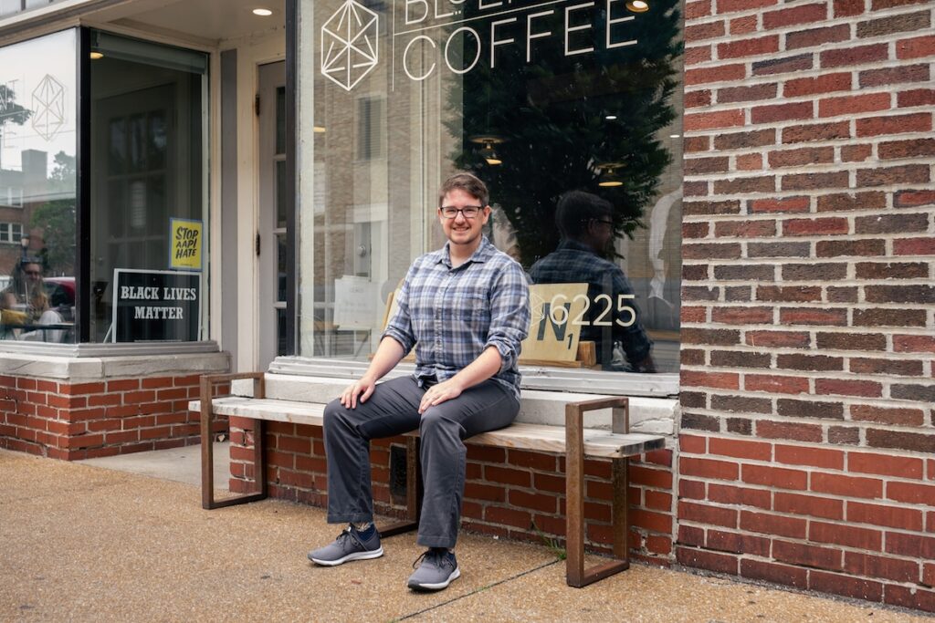 T DELMAR T sits on the wooden bench in front of our Delmar café and smiles at the camera