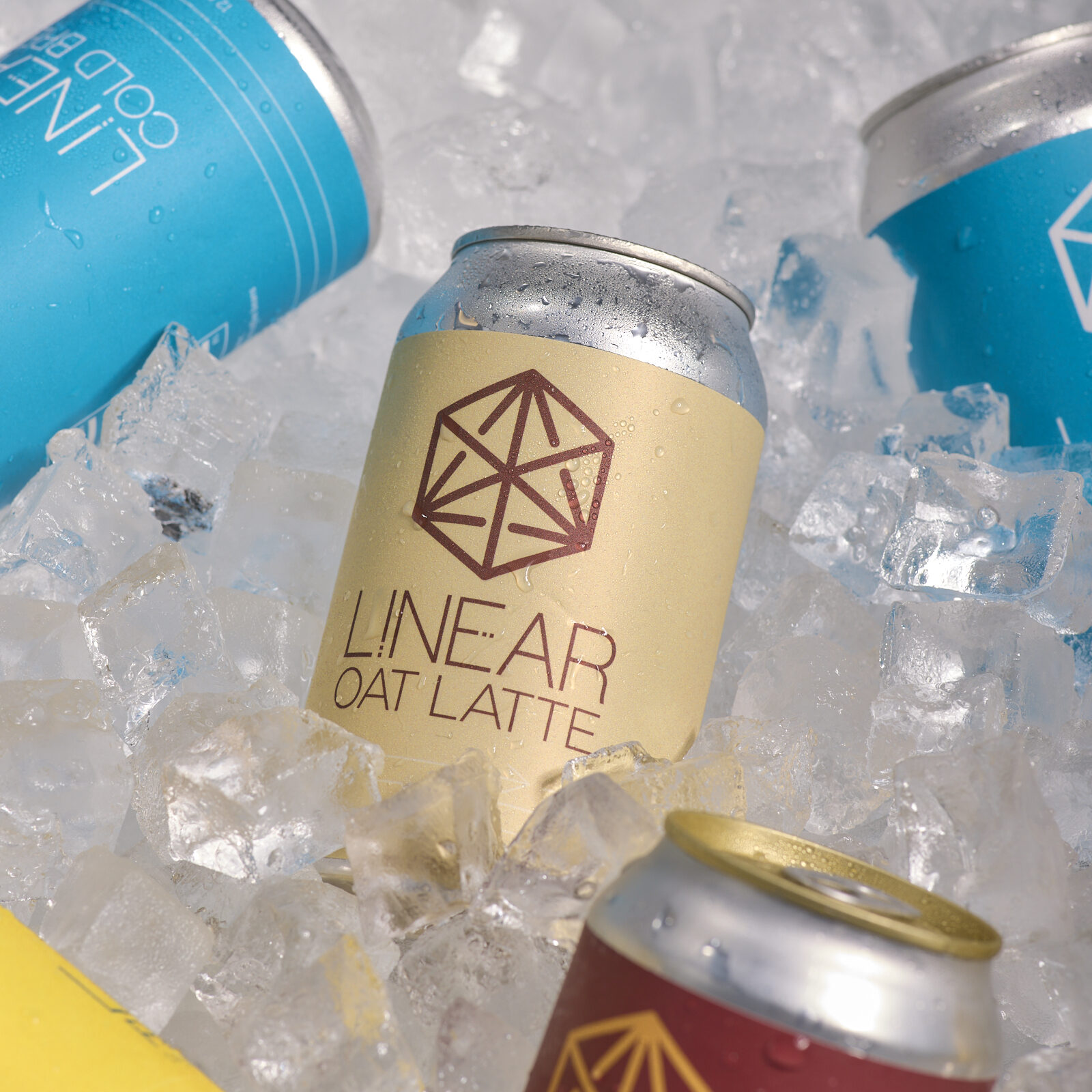 A can of Linear Oat Latte in a cooler full of ice surrounded by cans of Linear Cold Brew, Chai Soda, and Reviver
