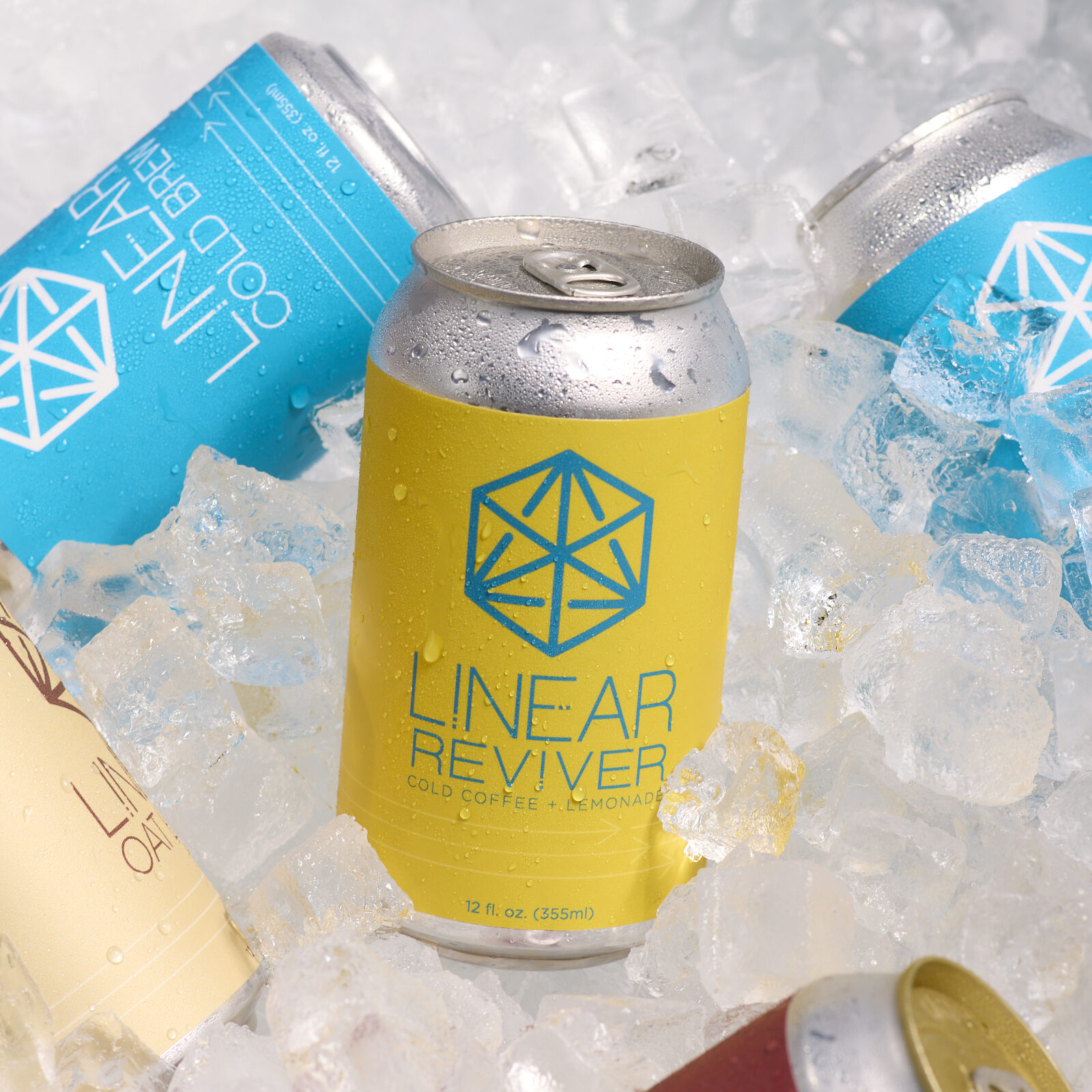A can of Linear Reviver in a cooler full of ice surrounded by cans of Linear Cold Brew, Chai Soda, and Oat Latte