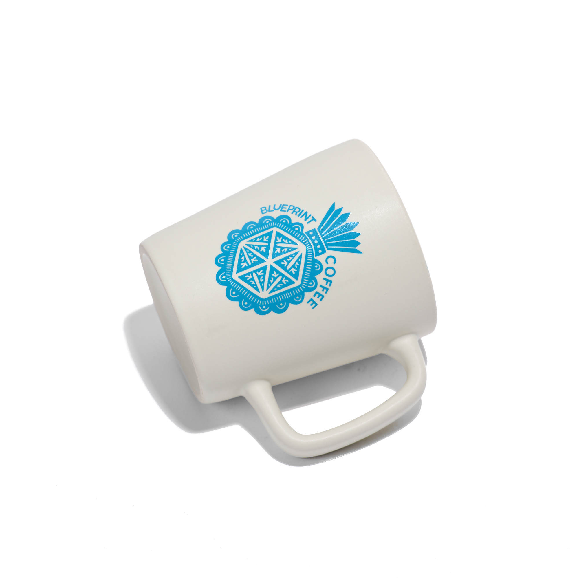 A white ceramic mug screenprinted with a blue illustrated "milagro" design
